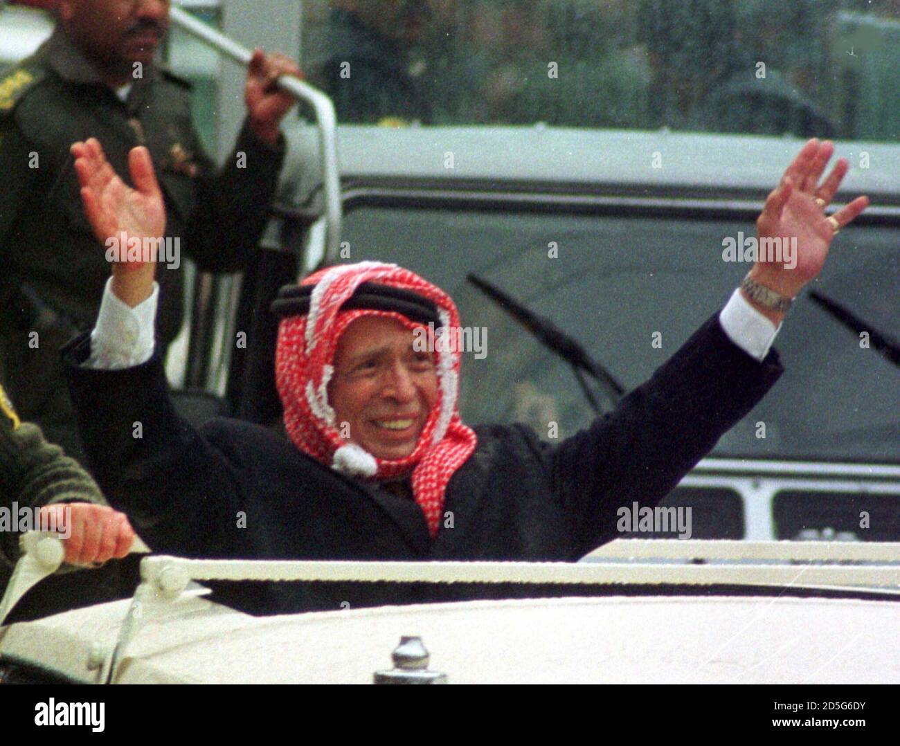 Jordan's King Hussein waves to crowds from his car in the center of Amman  January 19. King Hussein returned home to a tumultuous welcome in Jordan on  Tuesday, riding through rain-swept streets