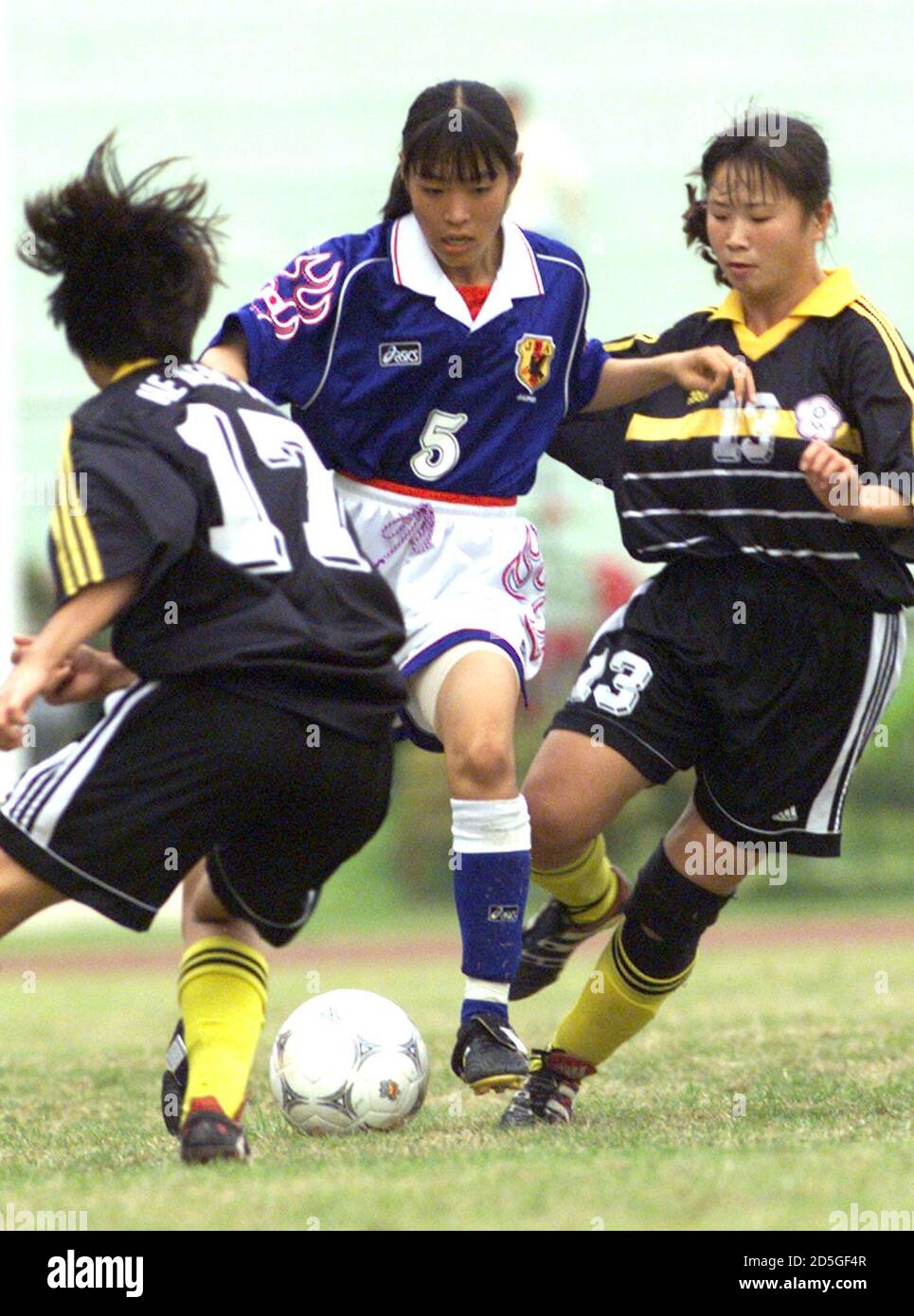 Tomoe Sakai (C) from Japan controls the ball as she is tackled by Taiwan's He Meng-hua and Chu Hsin-hsin (R) during the play-off of the 13th Asian Games women's soccer tournament played in Suphachalasai stadium in Bangkok December 17. Japan defeated Taiwan 2-1 and won the bronze medal.  PDN/FY/WS Stock Photo