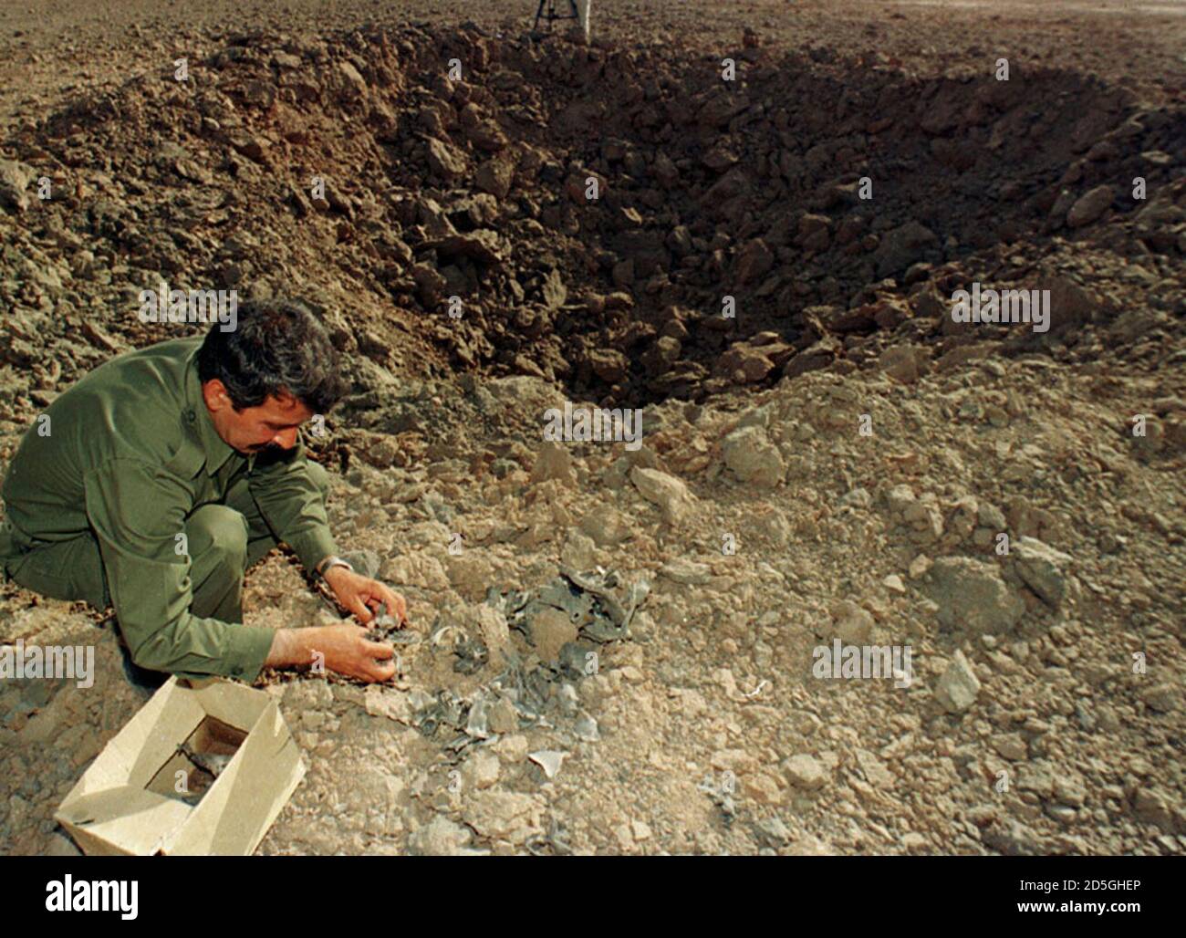 A Mujahideen fighter collects pieces of an Iranian missile June 11 which attacked a Mujahideen camp at Ashraf yesterday. Iraq said on Friday that Iran had fired three long-range misiles at an Iranian exile opposition group based inside Iraq. The official Iraqi news agency said that the camp belonged to Iranian opposition group Mujahideen Khalq. Ashraf is 100kms northeast of Bahgdad. FK/KM Stock Photo