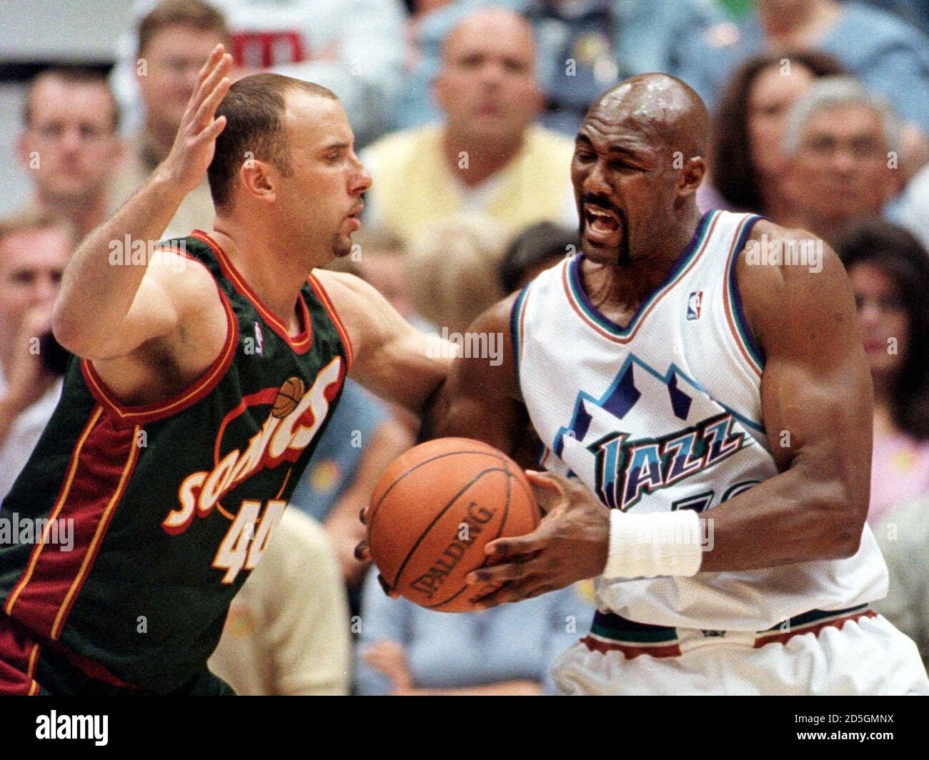 Utah Jazz forward Karl Malone (R) grimaces while going to the basket  against Seattle Supersonics' center Greg Foster during the first quarter,  April 22 in Salt Lake City. Malone was called for