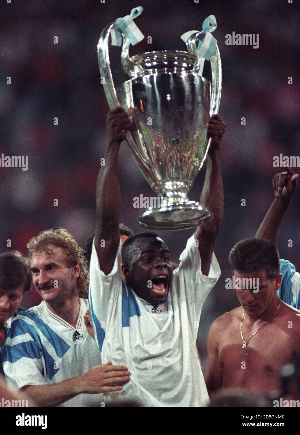Olympique Marseille's Basile Boli accompanied by teammate Rudi Voeller (L)  displays the European Champions Cup after his team beat AC Milan in the  European Champions Cup final May 26, 1993 with a