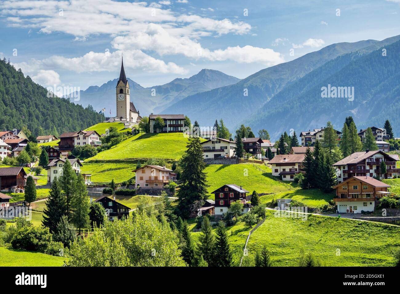 Beautiful Schmitten village at Albula pass in Grisons, Graubuenden, Switzerland with view of houses on green grassy hills, a lovely church on hilltop Stock Photo