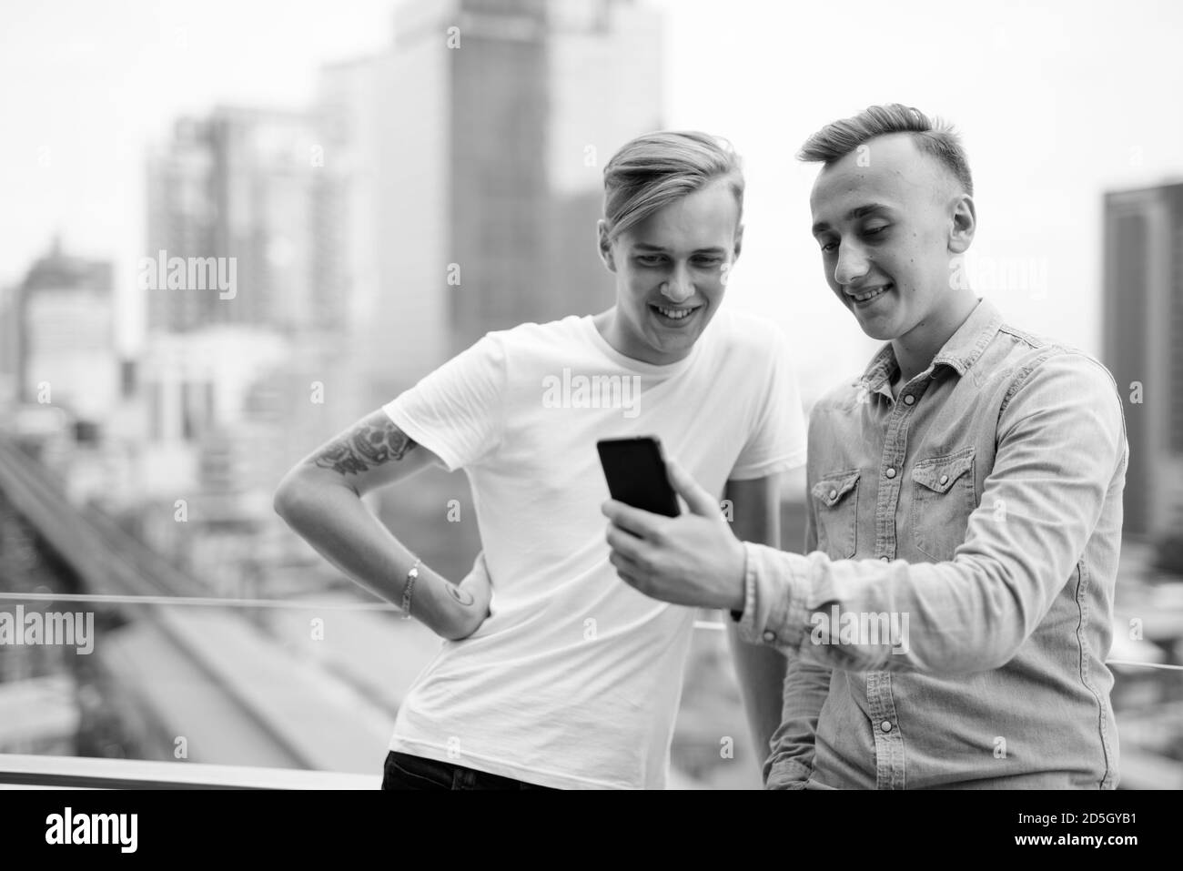 Two young handsome men with blond hair together against view of the ...