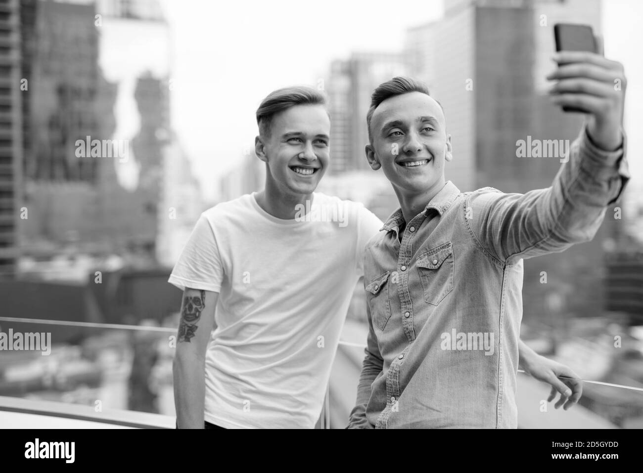 Two young handsome men with blond hair together against view of the ...