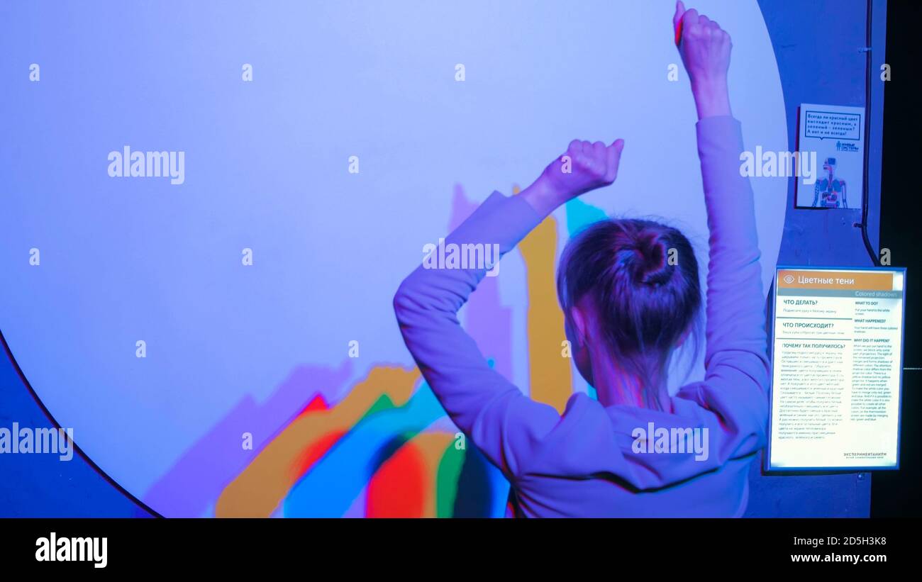 Interactive exposition in science museum. Colored shadows of dancing woman. Science, optical and physics concept Stock Photo