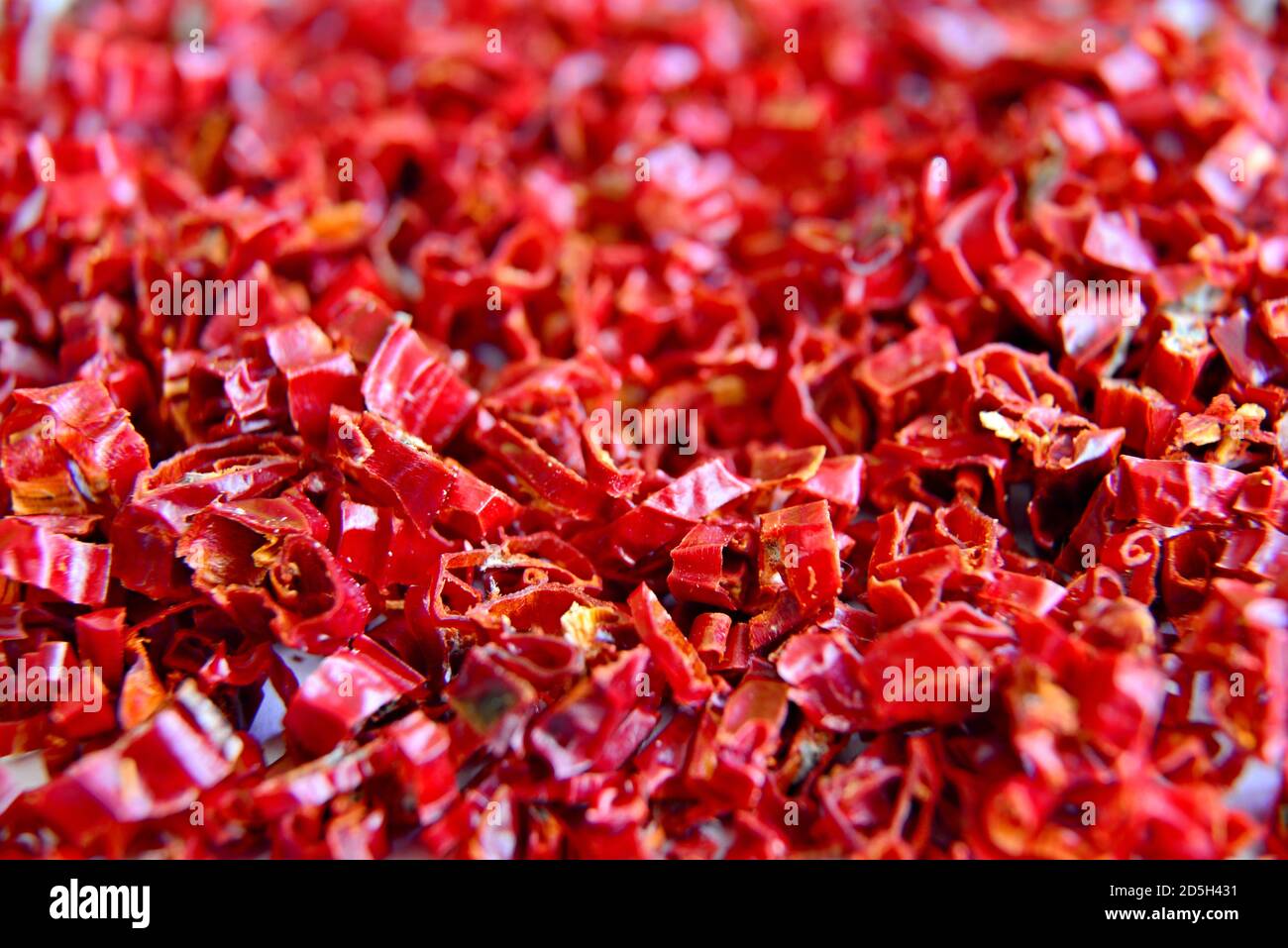 Dried red hot chili peppers. Chili Peppers sliced into small shavings. Crushed chili ready for cooking. Background with shavings of dried hot peppers. Stock Photo