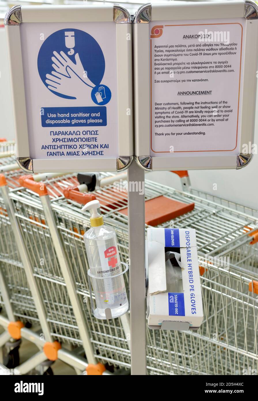 Hand sanitiser in dispenser with box of disposable plastic gloves and sign saying to use them Stock Photo
