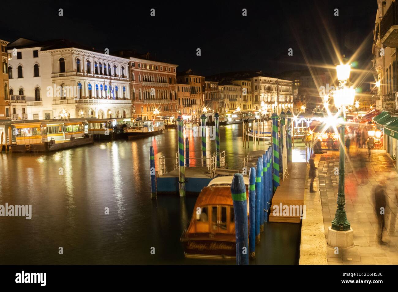 View alongside the Grand Canal and water taxis moving along it at night time Stock Photo