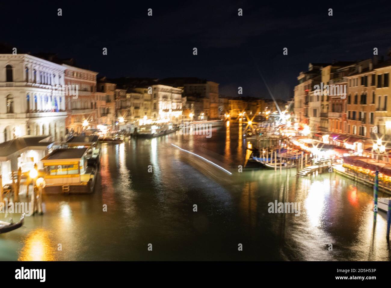 View of the Grand Canal shimmering whilst water taxis sail on it at night time Stock Photo