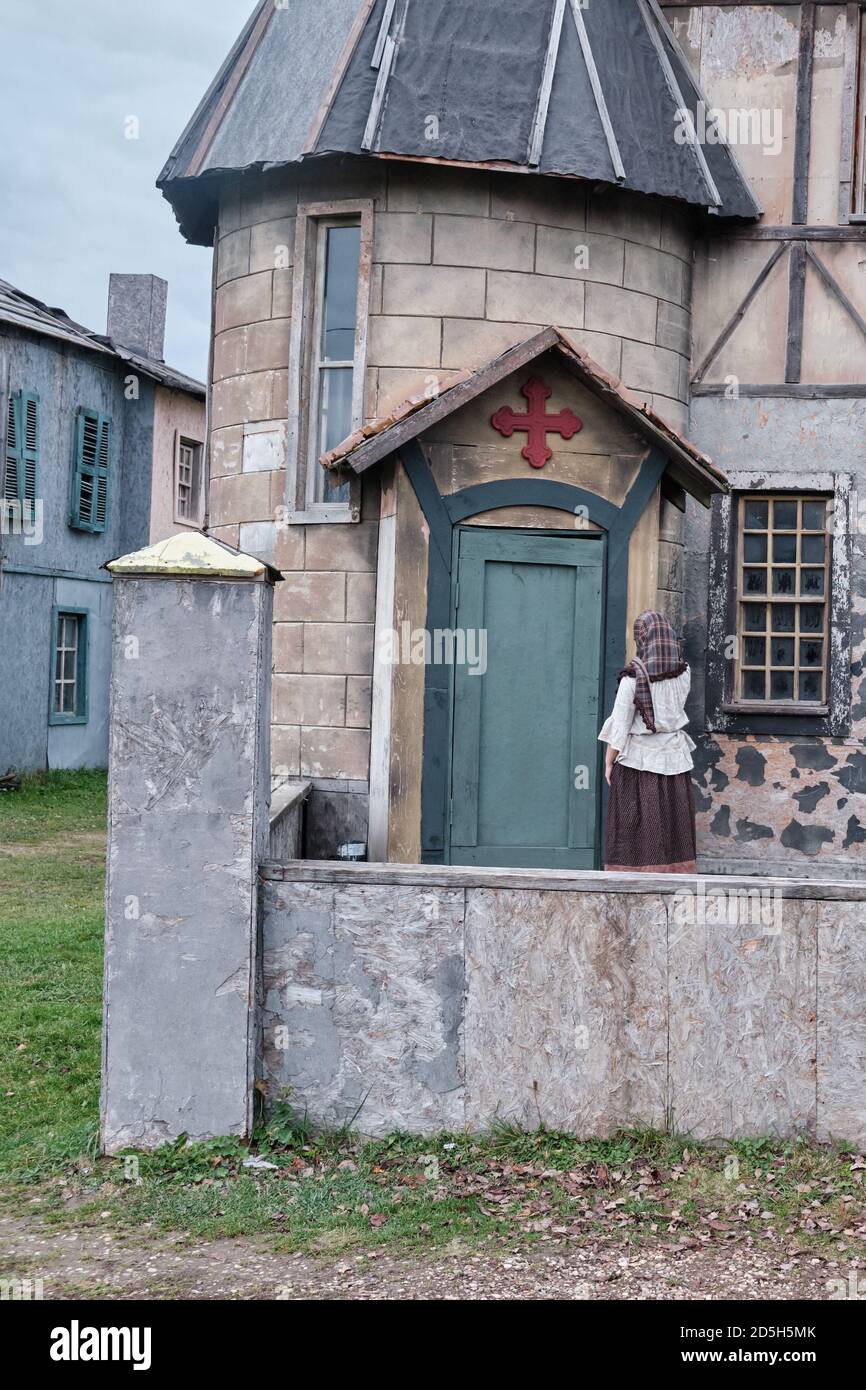 A woman in an old dress in the courtyard of an old catholic Church with ...