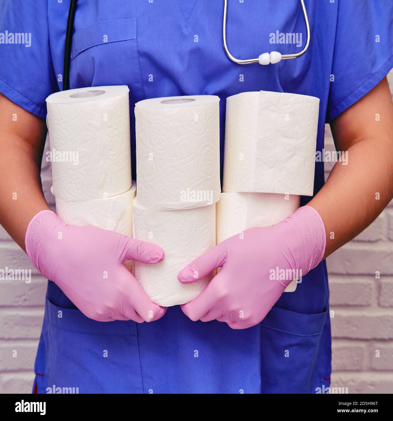 A doctor in protective gloves holds rolls of toilet paper. Lots of