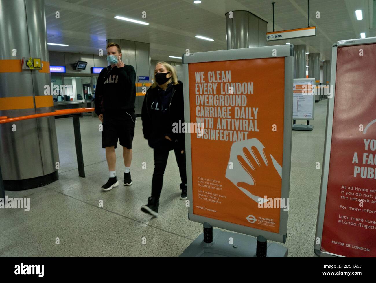 Passengers at a London underground train station, with signs advising