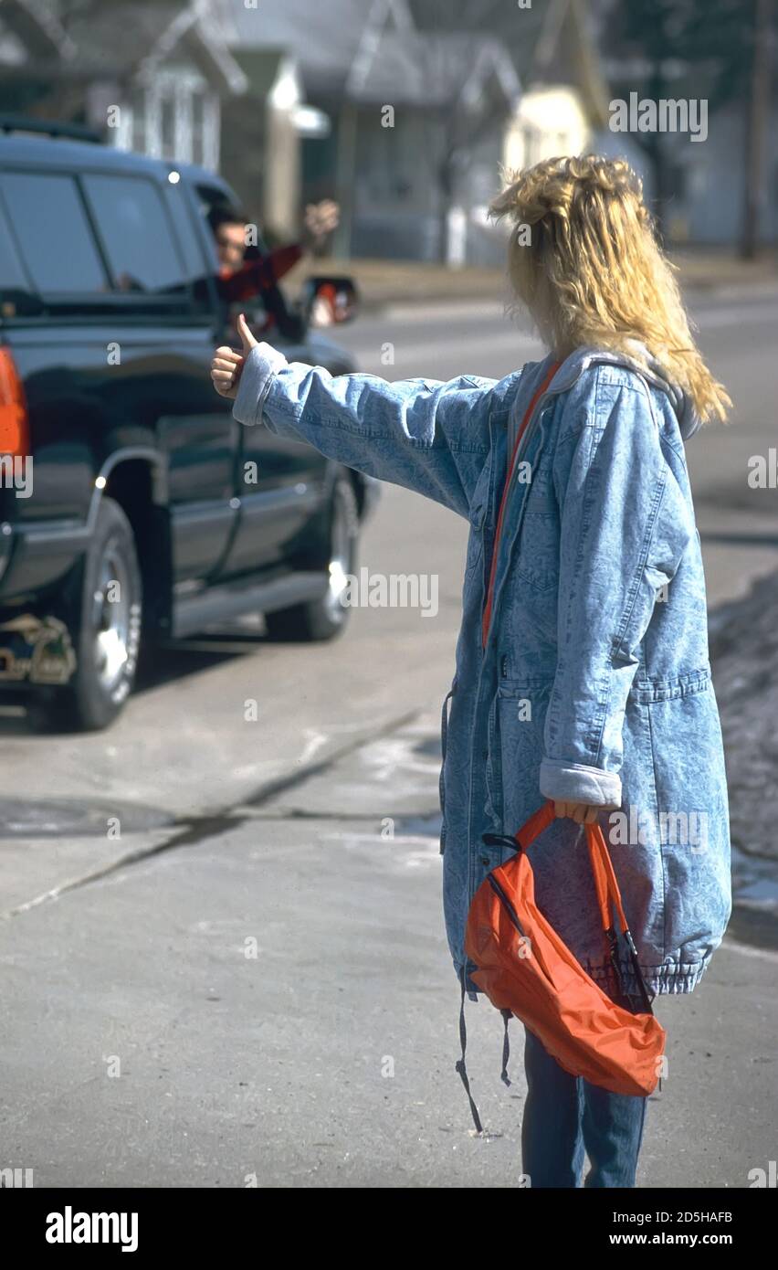 runaway young Female hitch hiker running away from home has an offer for a ride from a male adult Stock Photo