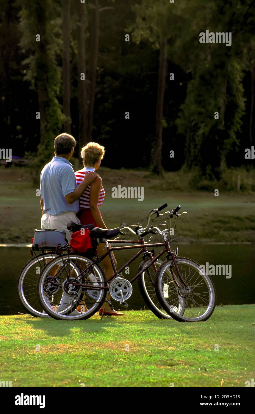Middle aged couple pause while riding bicycles for recreation and exercise Stock Photo