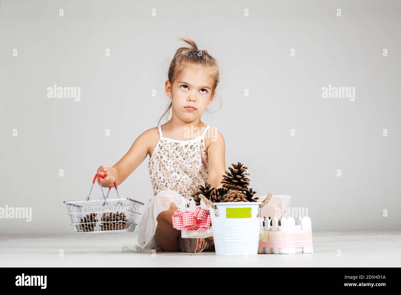 little caucasian girl playing with pinecones Stock Photo - Alamy