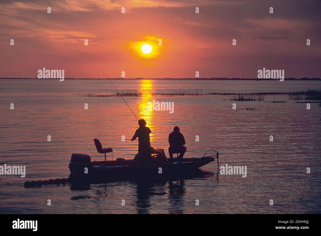 Family fishes for bass from a boat at sunset on Lake Okeechobe, Florida Stock Photo