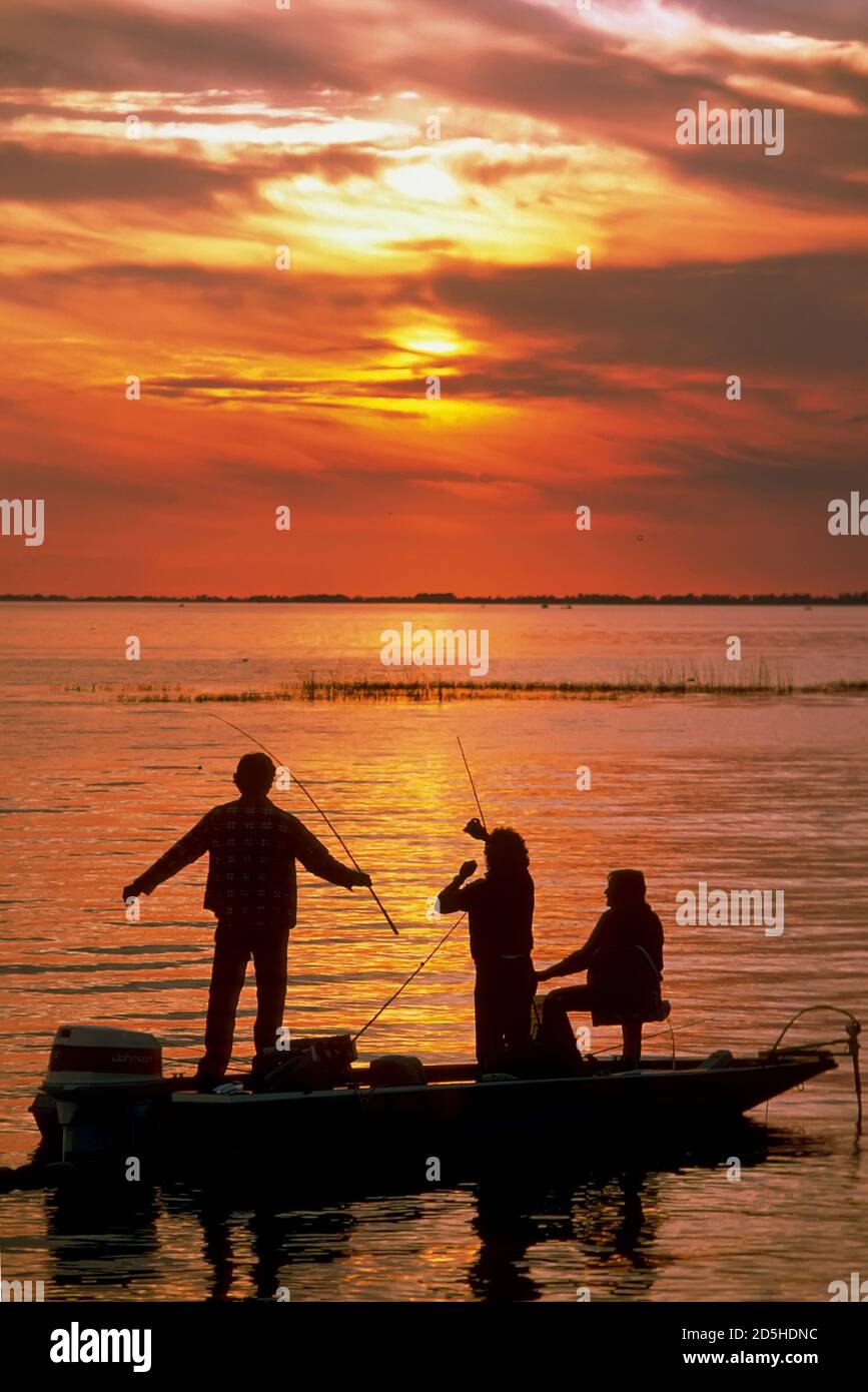 Family fishes for bass from a boat at sunset on Lake Okeechobe, Florida Stock Photo