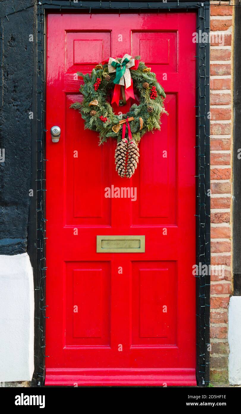 WINSLOW, UK - December 29, 2019. Red front door of UK home at Christmas with an Xmas wreath ornament Stock Photo