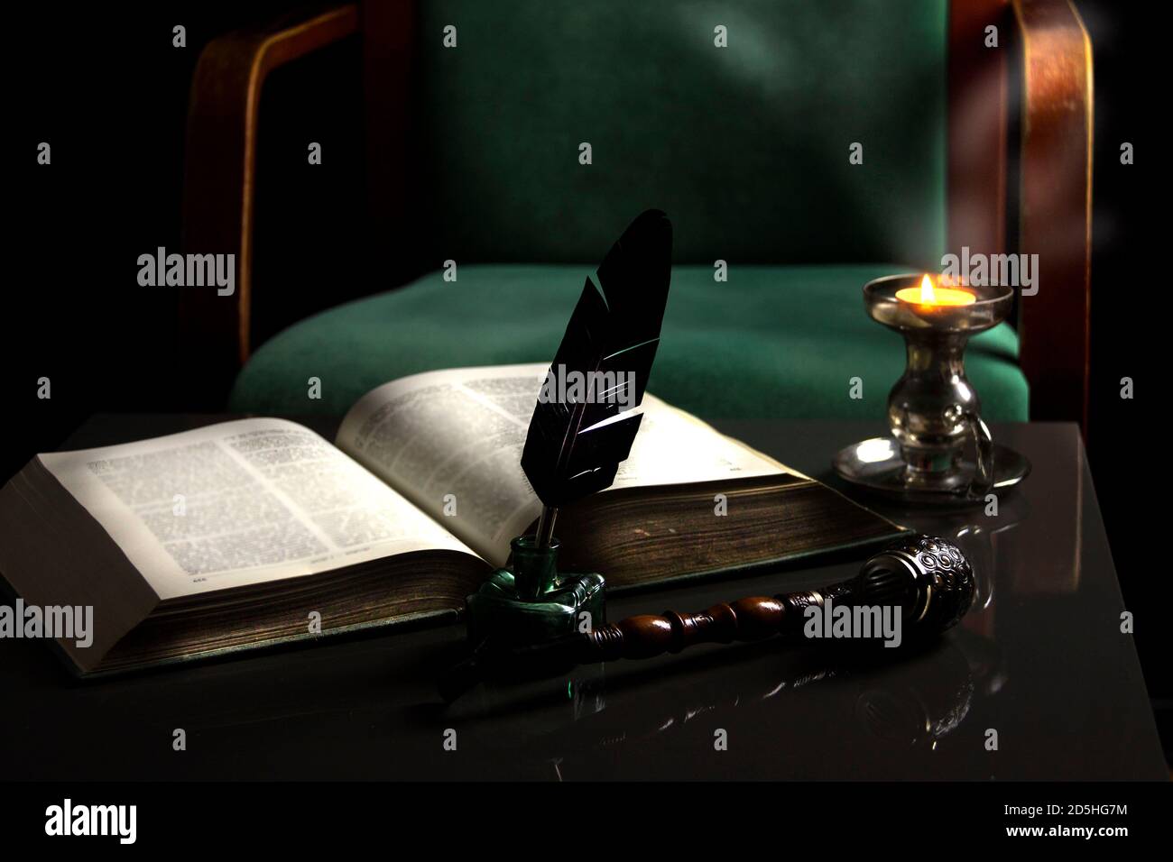 Feather pen with inkwell and old book. Vintage background. Stock Photo