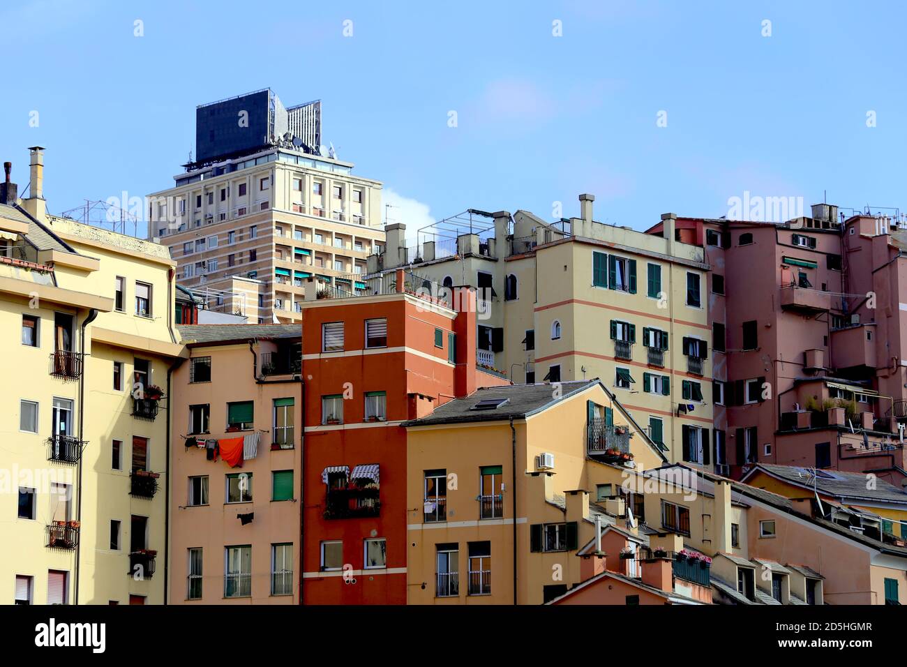 Genoa, Italy. Wide view of colorful houses in Genoa historic city center against a contemporary building and a blue sky in the San Agostino hill. Stock Photo