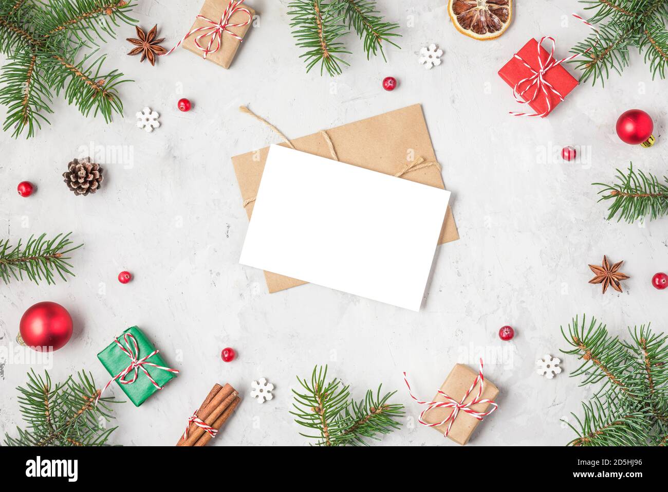 Christmas or Happy New Year greeting card in frame made of fir tree branches, holiday decorations and gift boxes on concrete background. flat lay. top Stock Photo