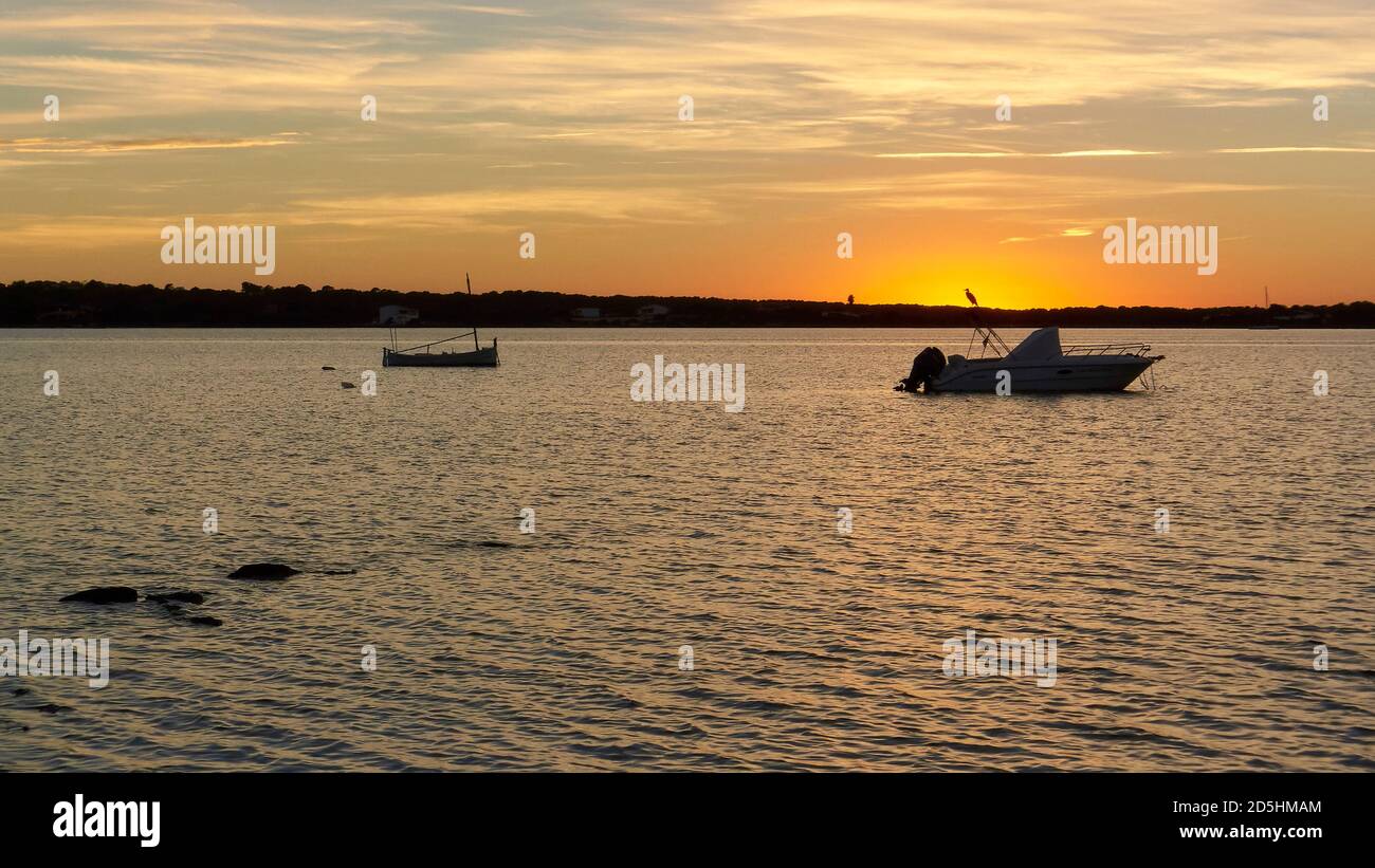 Sunset at Estany des Peix with anchored boats and heron silhouette against sun (Ses Salines Natural Park, Formentera, Mediterranean Sea, Spain) Stock Photo