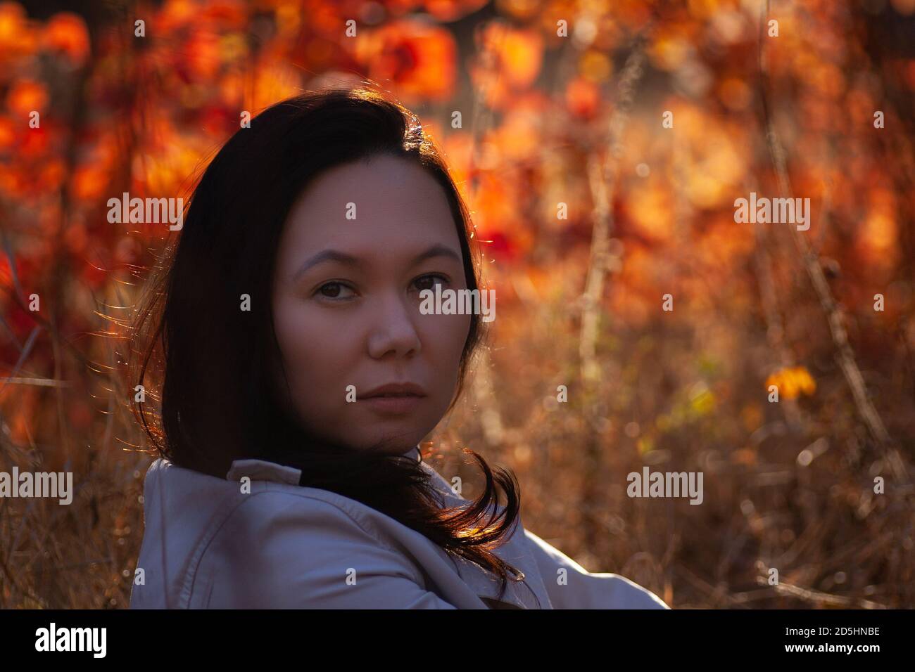 portrait of an Asian young woman in an autumn forest at sunset Stock Photo