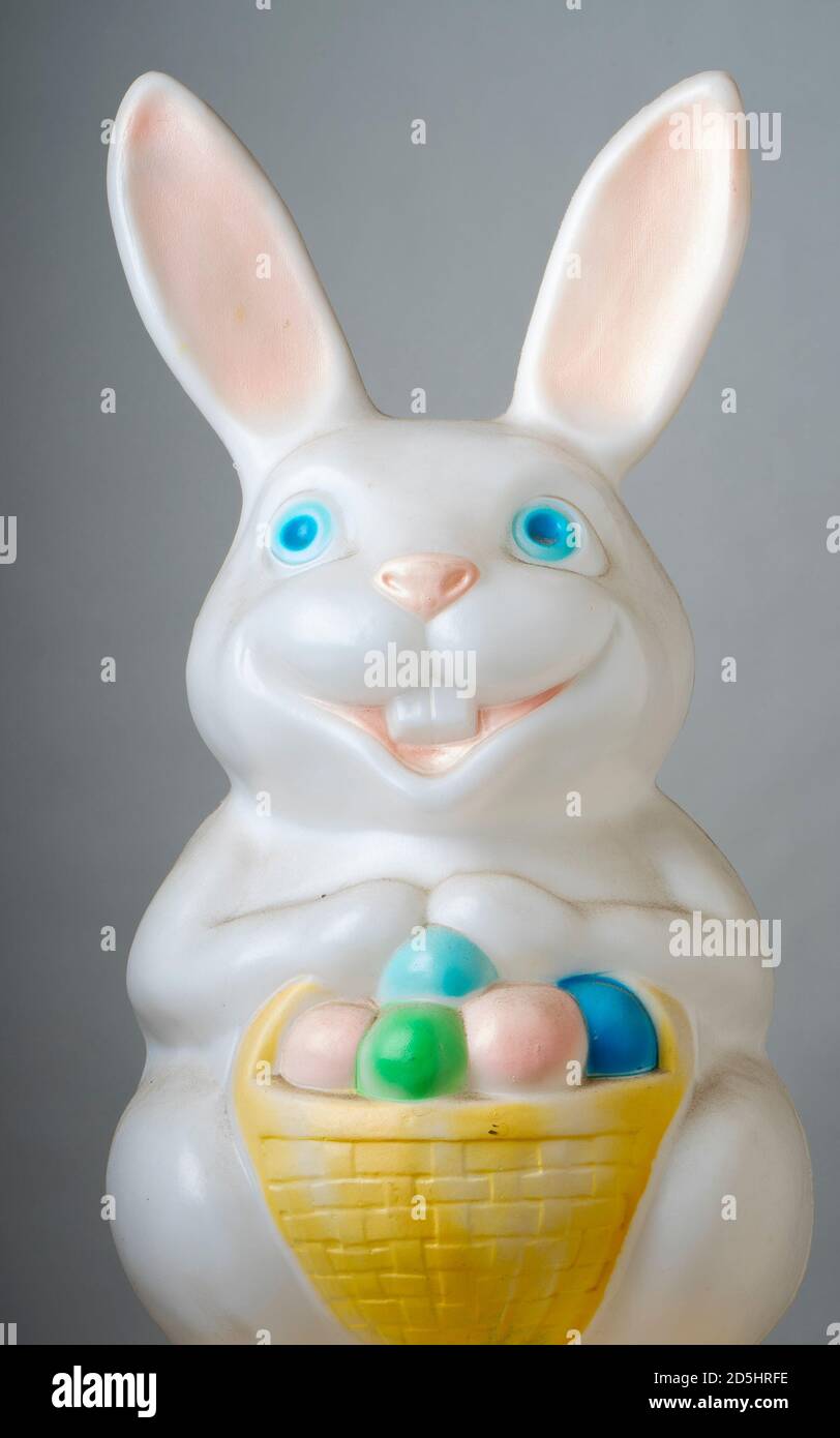 Plastic Easter bunny holding basket full of colored eggs. Stock Photo