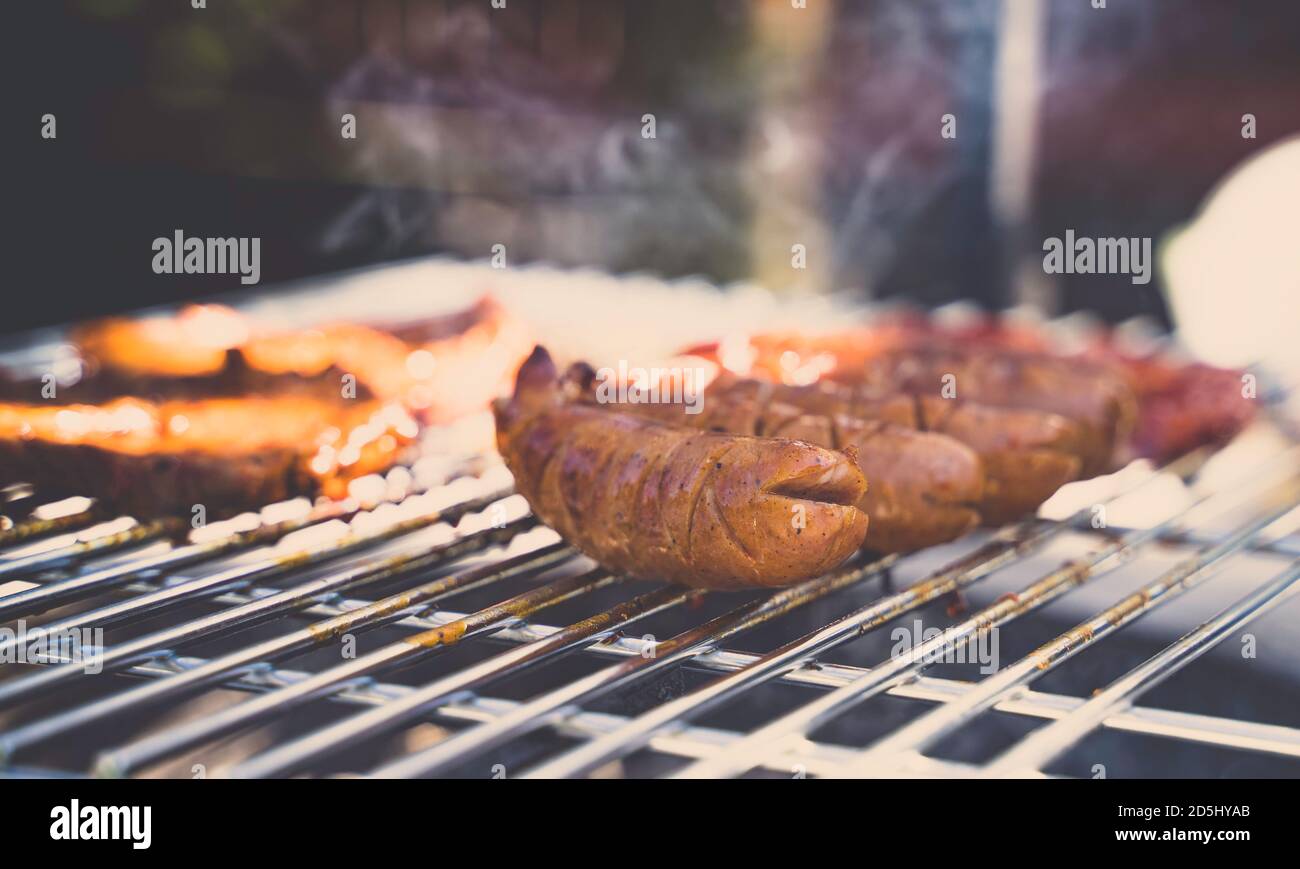 Sausages on a grill. Barbecue in the garden. Smoke in the background. Stock Photo