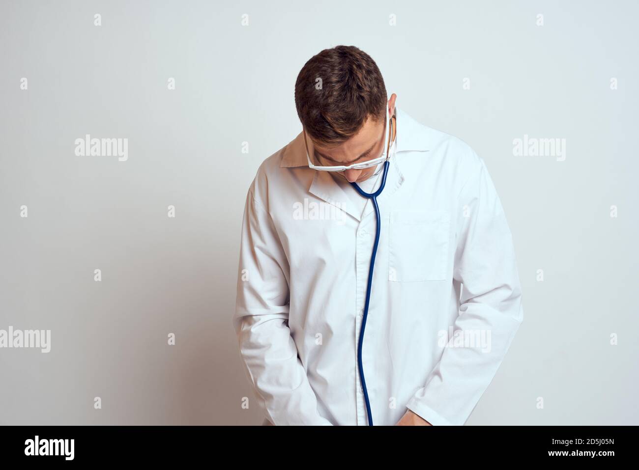 doctor in a medical gown with a stethoscope and glasses on a light ...