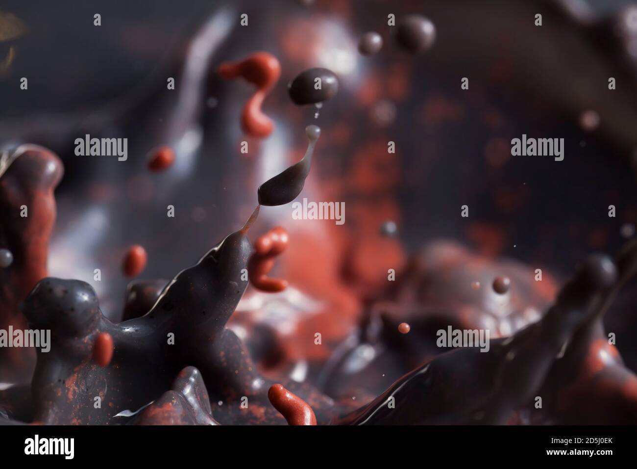 Lava bubbling inside a volcano - Black and red paint splashing creating lots of paint bubbles and droplets. Stock Photo