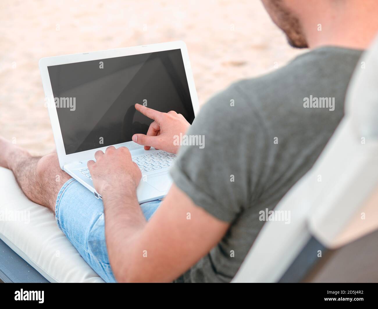 Freelancing concept. Man using a touch screen computer laptop with blank black computer screen. Stock Photo