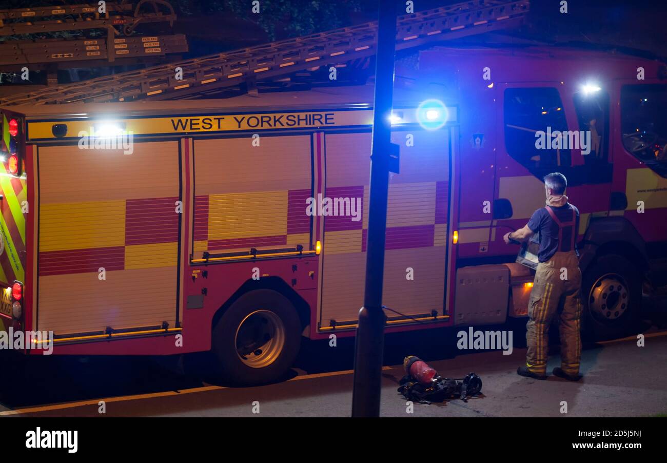 Firefighter getting suited up with equipment beside a fire engine or fire truck. Stock Photo