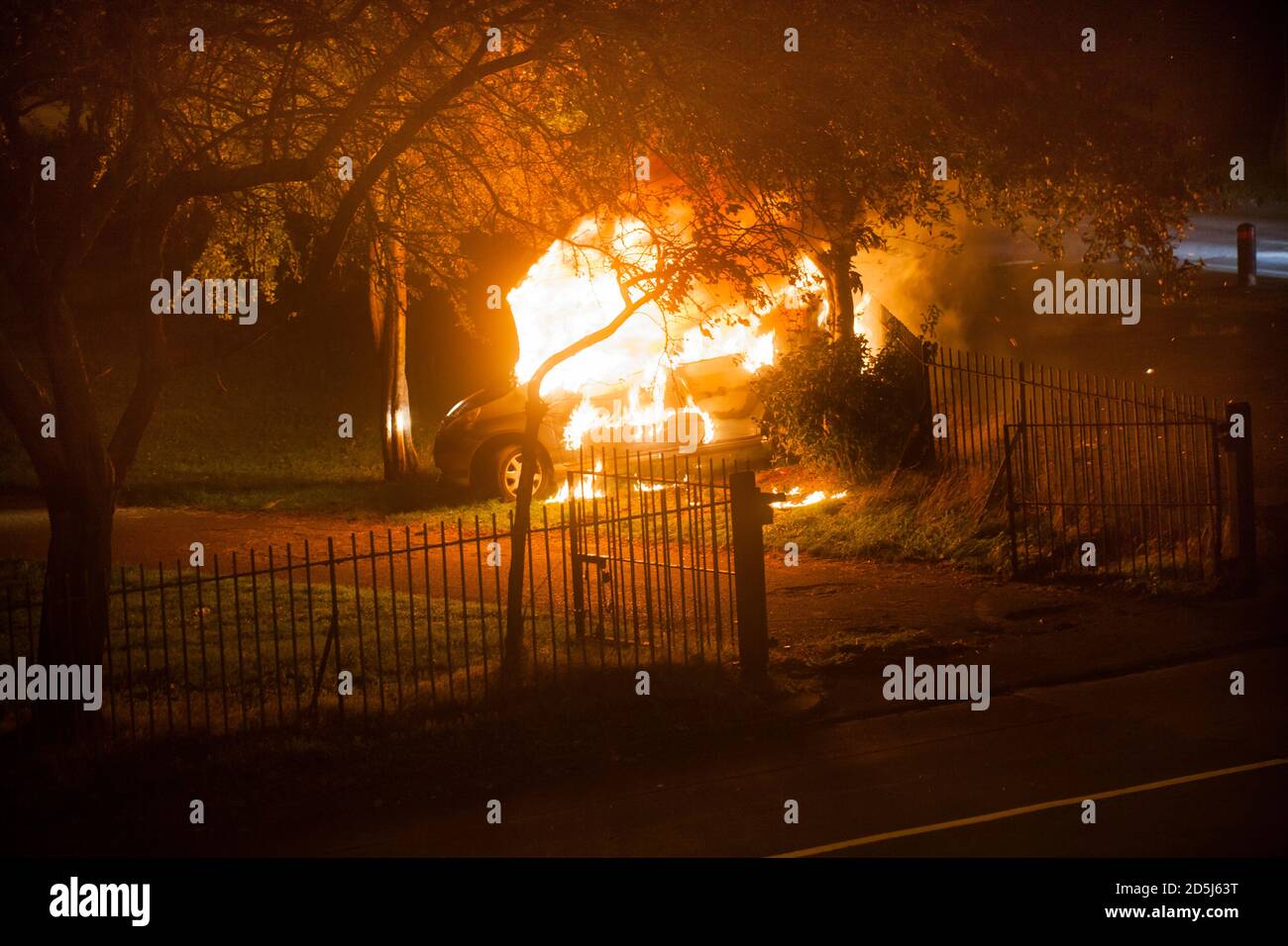 An abandoned car on fire in a public park.Car burning ,lots of flames and smoke. Stock Photo