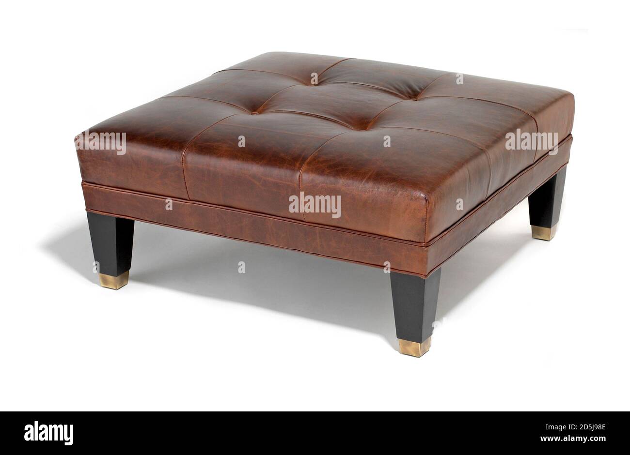 Short, brown leather footstool with black and gold legs Stock Photo Alamy