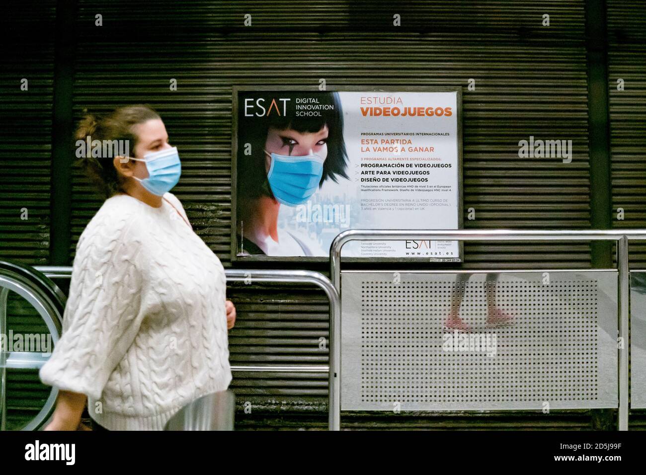 Valencia, Spain. 13th Oct, 2020. A woman wearing a face mask walks past an advertisement for video games at Angel Guimera Station. Credit: SOPA Images Limited/Alamy Live News Stock Photo