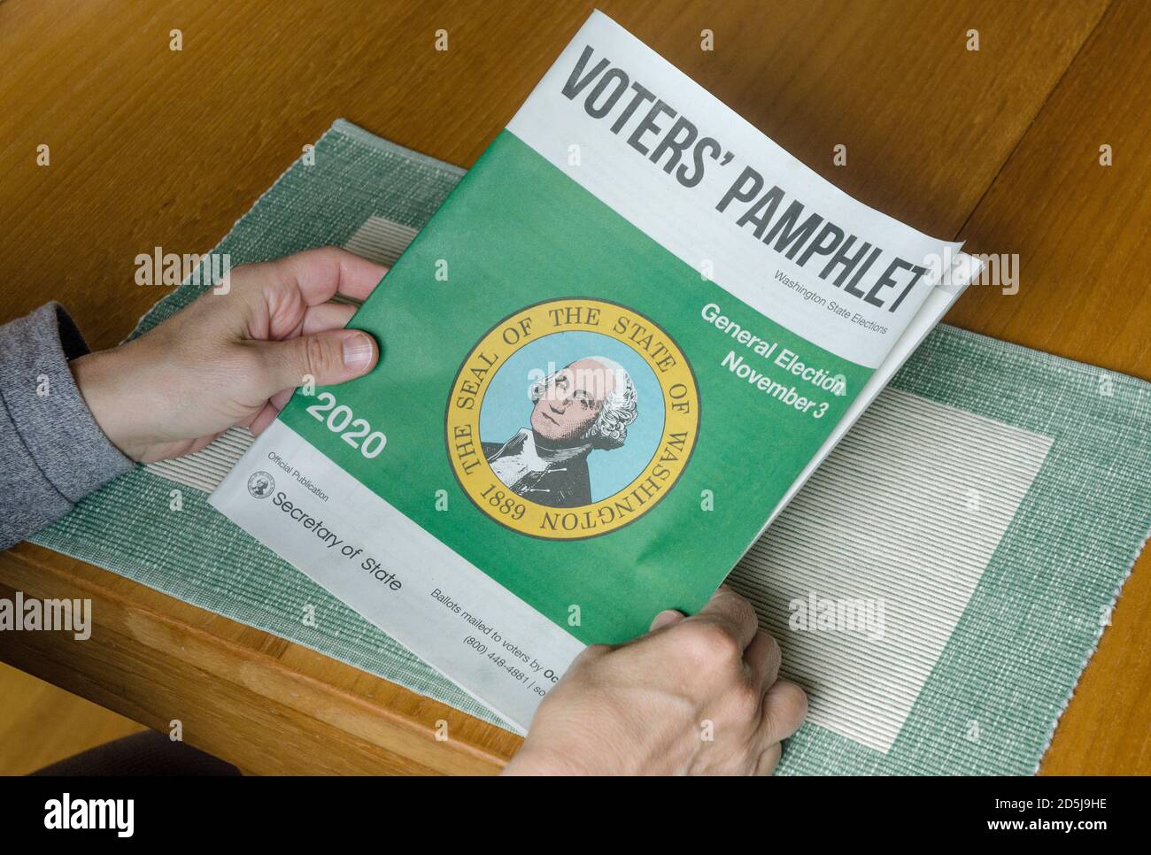 A voter holds the Voters' Pamphlet, which contains information on candidates and statewide measures for the public. Stock Photo