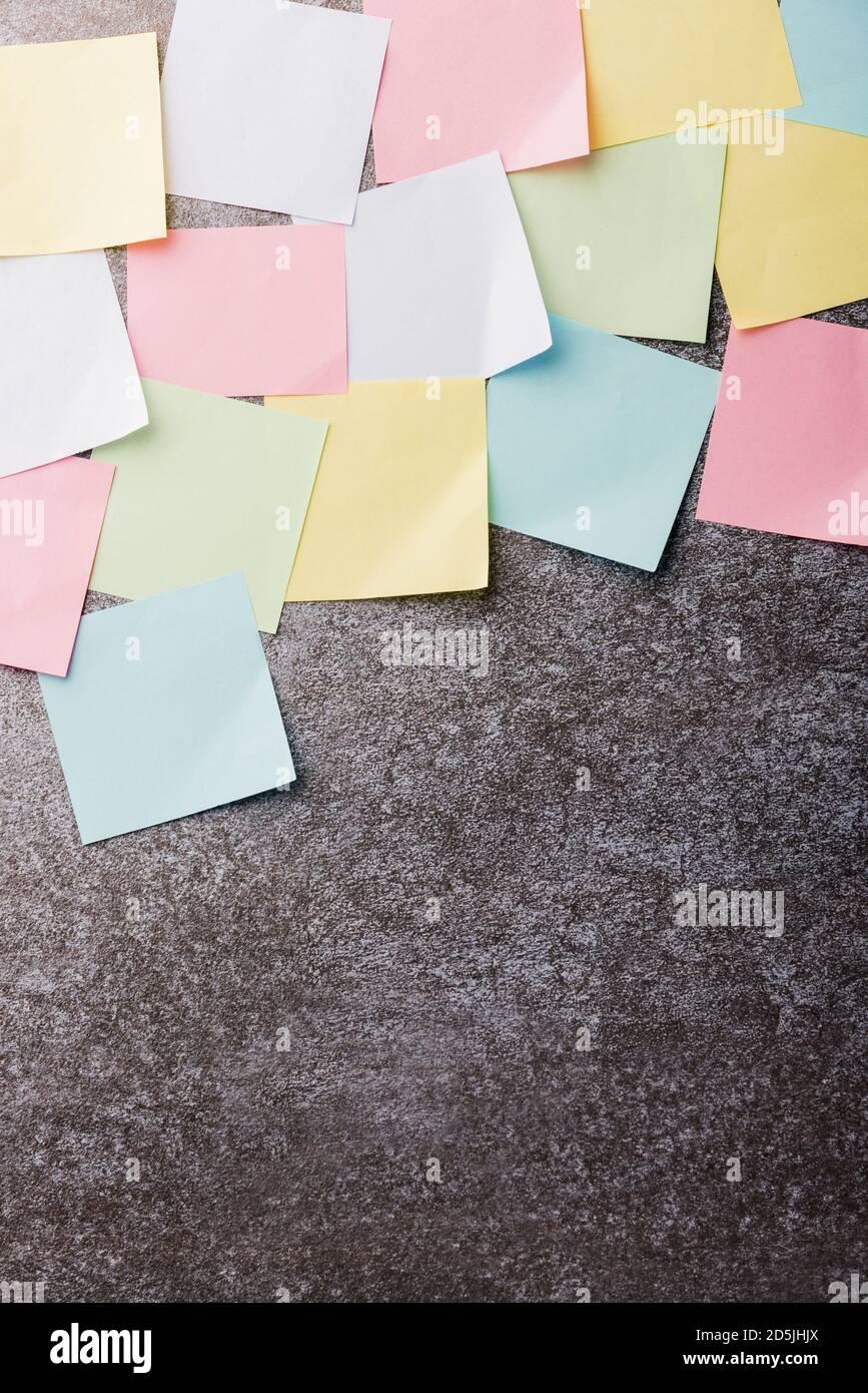 Many blank multicolored paper stick note list on concrete wall ...