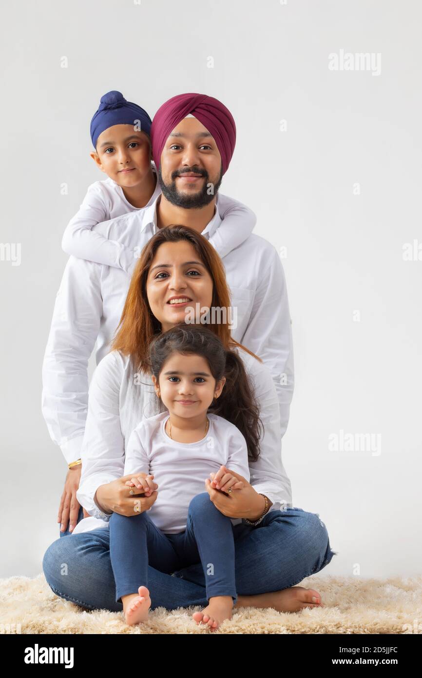 A SIKH FAMILY SITTING DOWN ON RUG TOGETHER AND HAPPILY POSING Stock ...