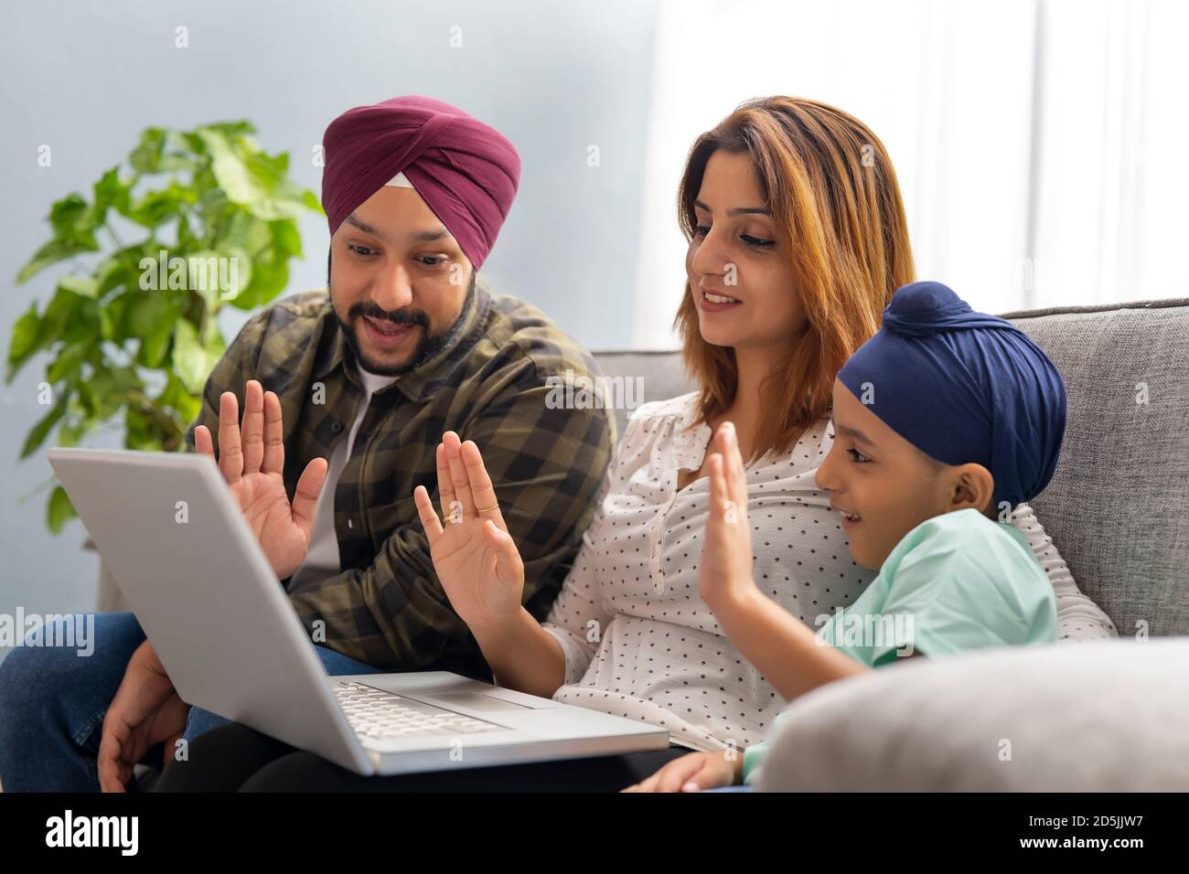 A SIKH FAMILY TALKING TO FRIENDS OVER VIDEO CONFERENCING IN A LAPTOP Stock Photo