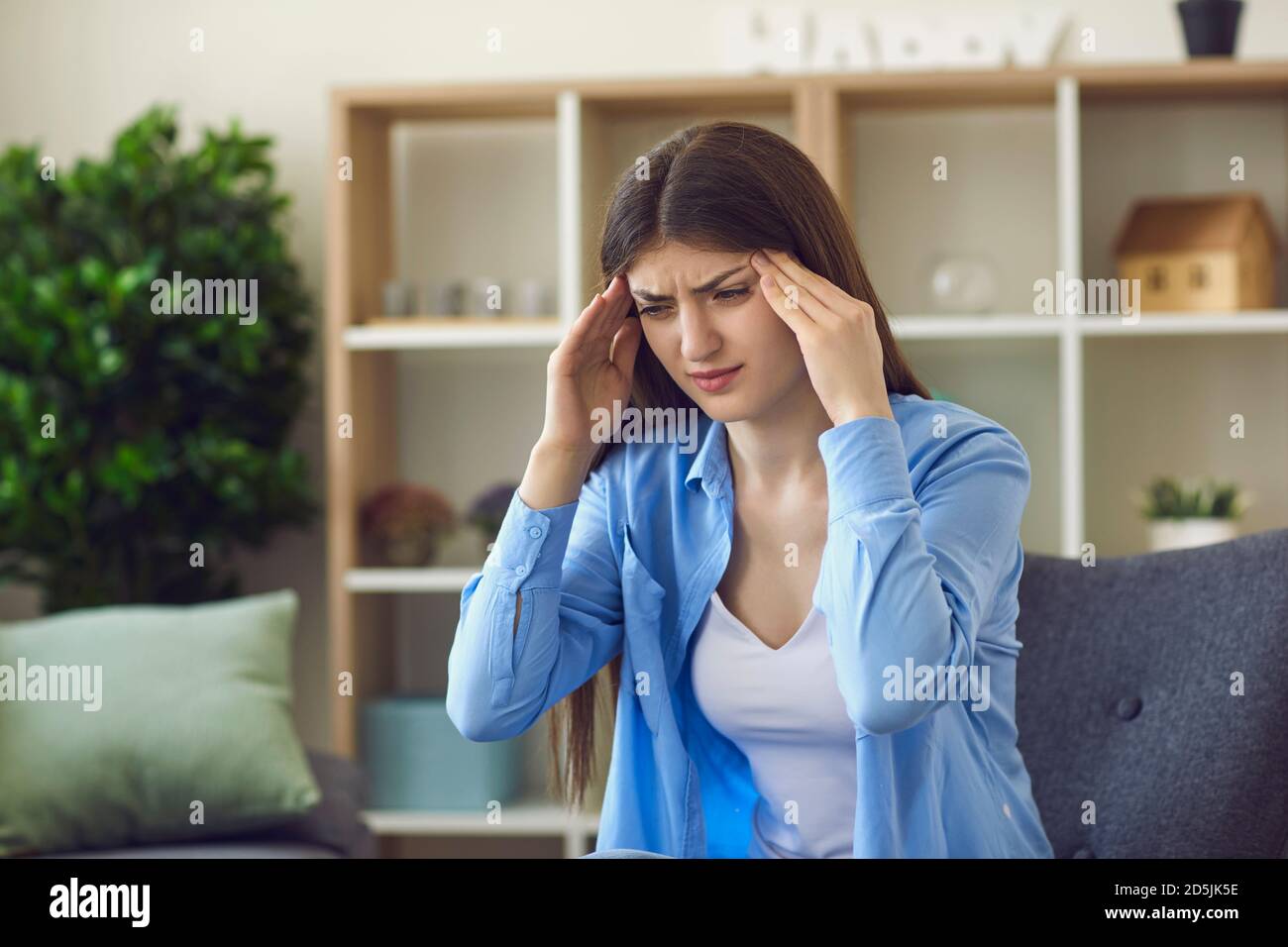 Young stressed woman touching temples with hands and feeling bad Stock Photo
