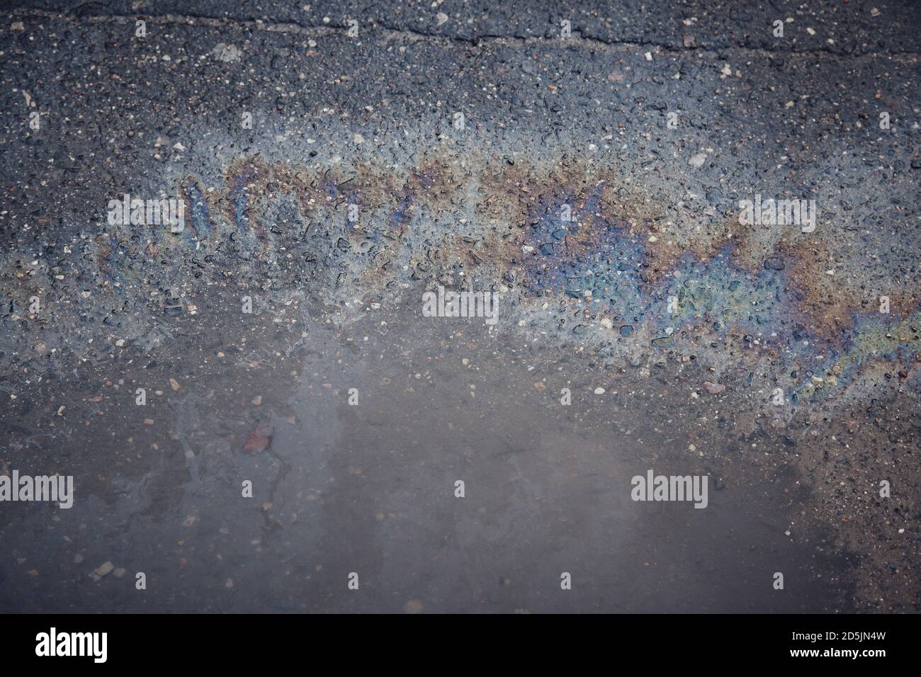 Gas stain on wet asphalt caused by a leak under a car or truck Stock