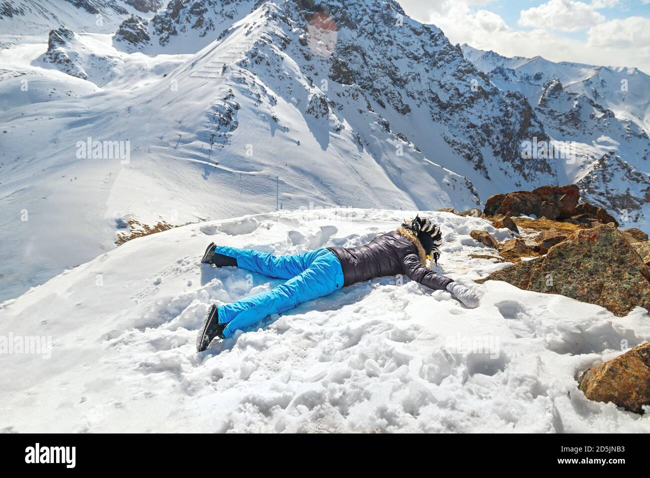 Acrophobia woman lie on top of a snowy rock cliff edge. Fighting the fear of heights concept Stock Photo