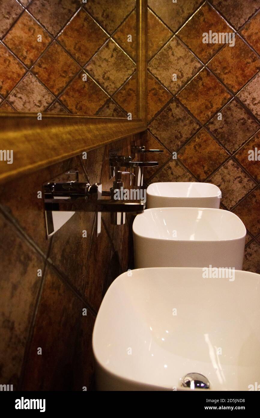 Golden brown design water closet room with bronze color tile on a wall and big mirror three