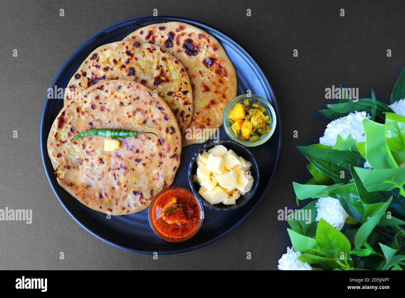 Aloo / Alu Paratha or Indian Potato stuffed Flatbread. Served with butter for breakfast, pickle and masala potatoes among with masala tea / chai. Stock Photo