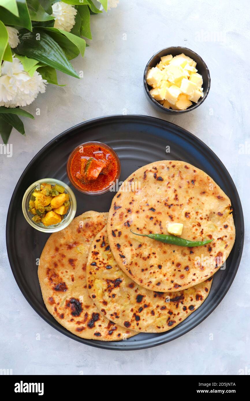 Aloo / Alu Paratha or Indian Potato stuffed Flatbread. Served with butter for breakfast, pickle and masala potatoes among with masala tea / chai. Stock Photo