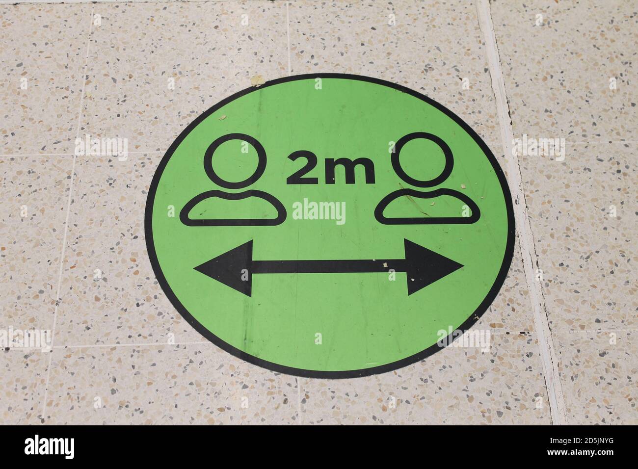 A round green social distancing sticker on the floor informing shoppers to stay two metres apart during the covid pandemic Stock Photo