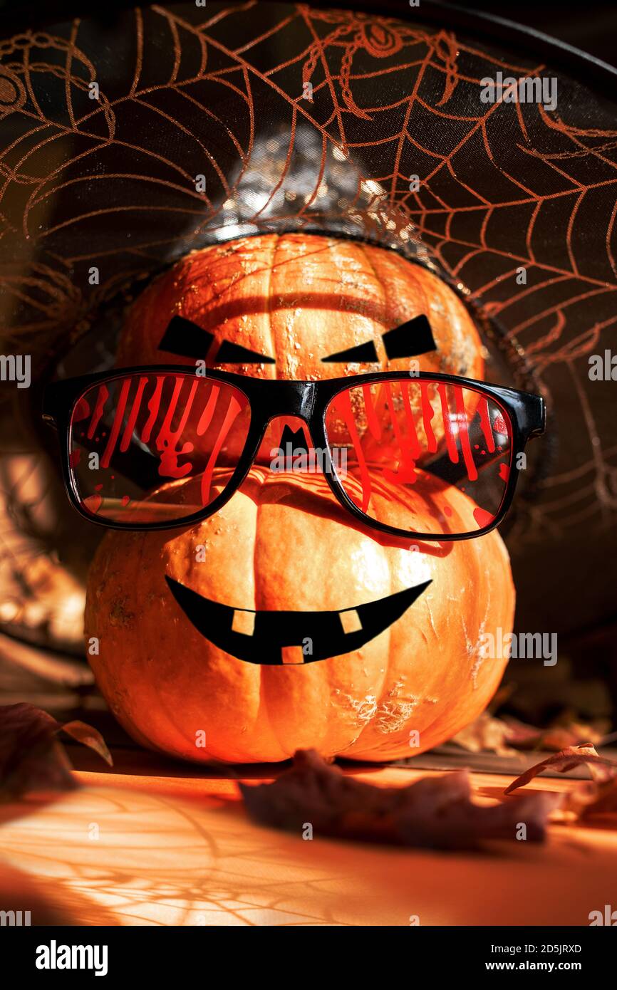Two Halloween pumpkins standing one on top of other and painted as Jack's lantern in bloody glasses and witch hat. Stock Photo