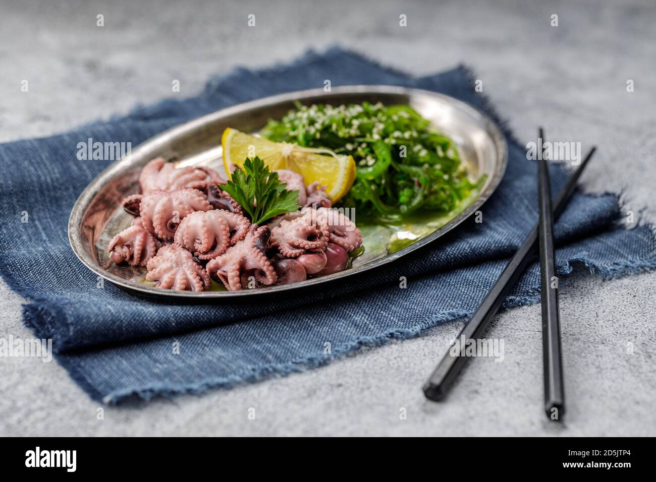 Traditional asian food. Delicious boiled octopus with fresh wakame salad. Stock Photo