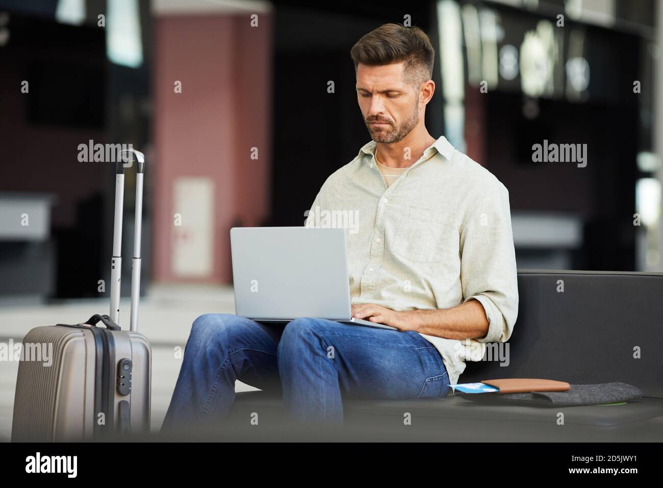 Young businessman working on laptop while sitting in waiting room at the airport Stock Photo